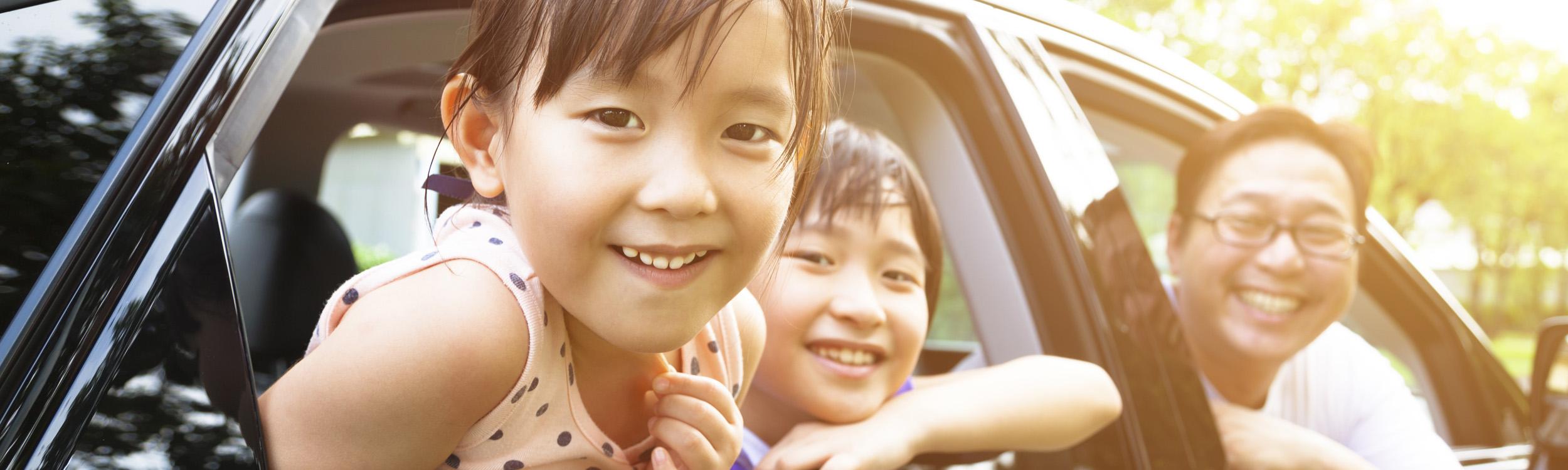 Asian family of 3 smiling from car